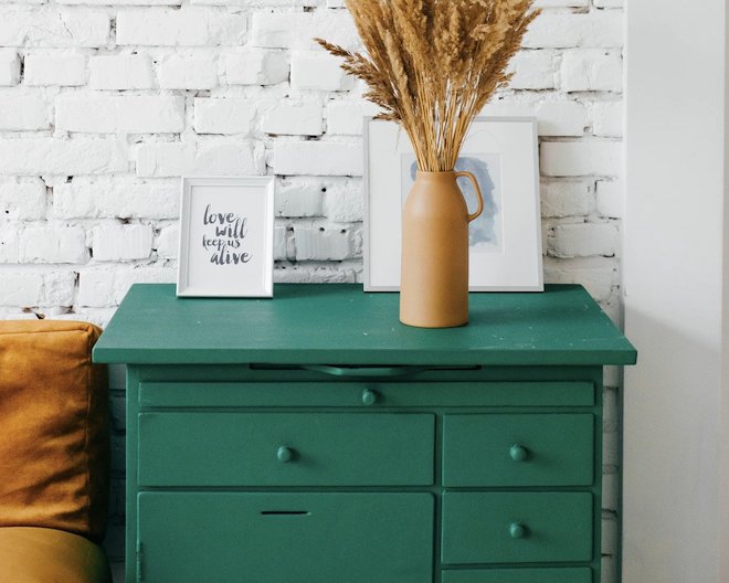 Photo of a green wooden cabinet, in a home with decorations on top.